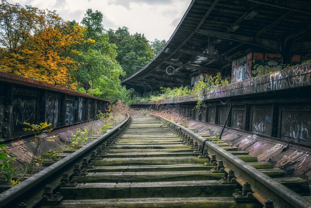 Abandoned railway station with overgrown tracks at sunset