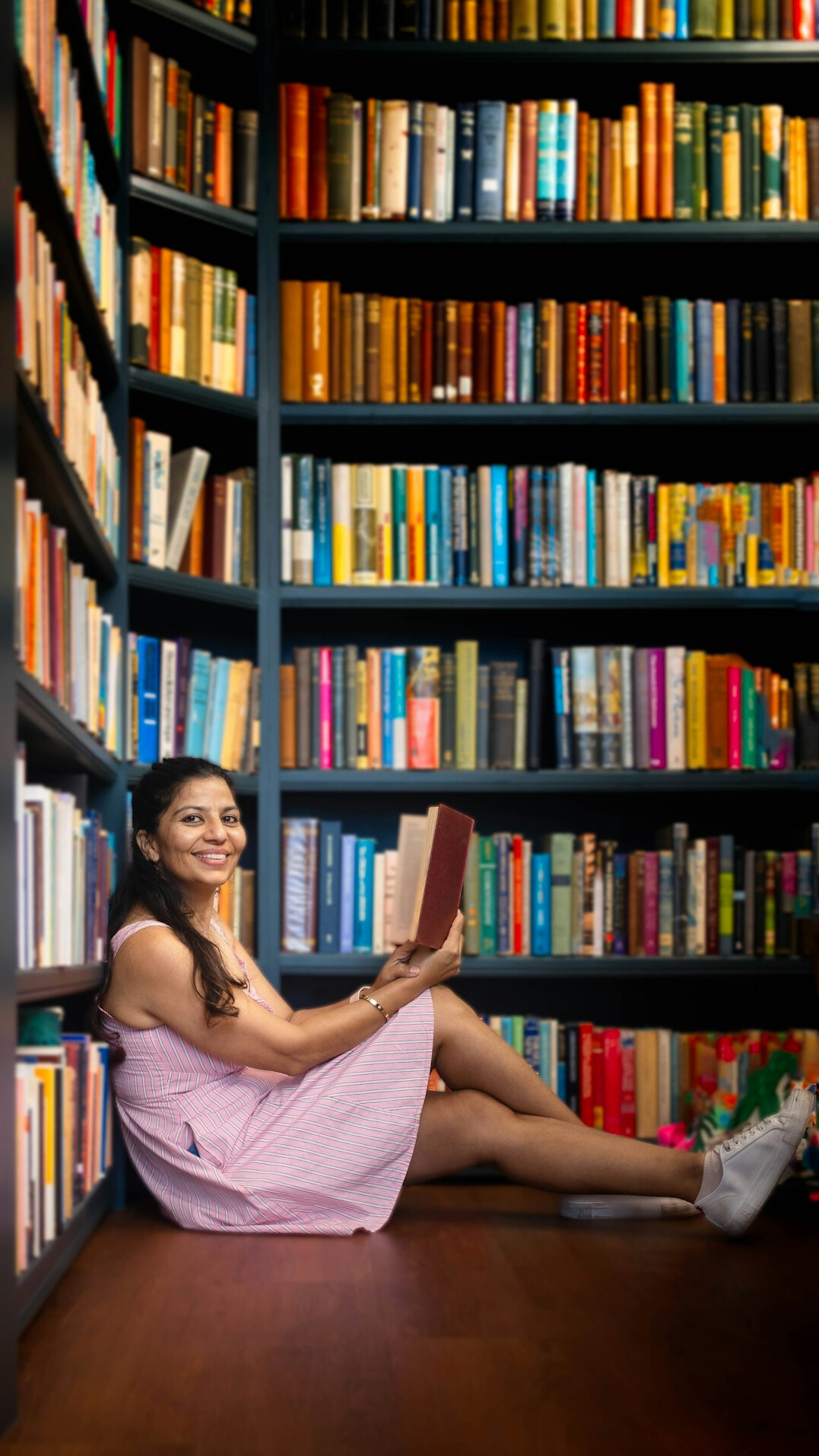 Smiling young woman with a book in a bright library